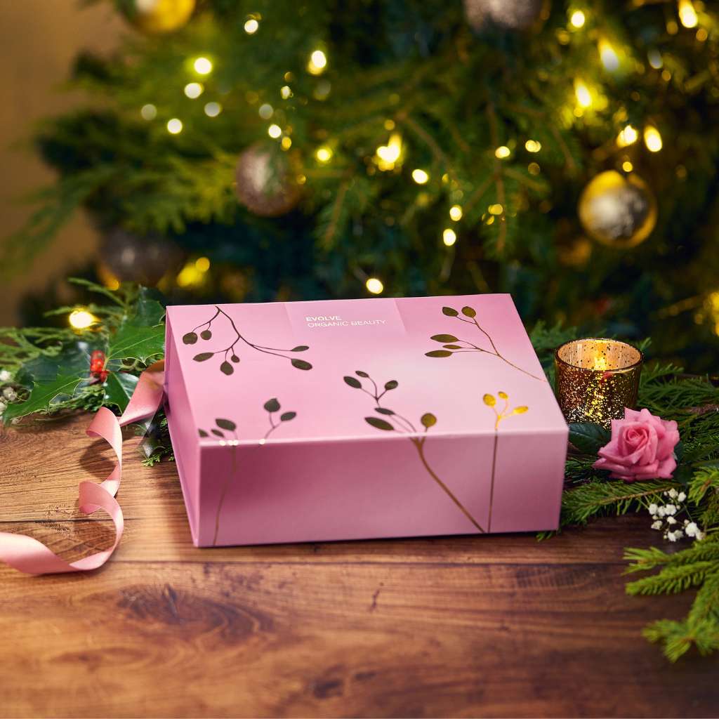 Purple gift wrapping box with gold leaves in front of chrismas tree